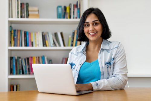 Woman sitting at a laptop smiling.